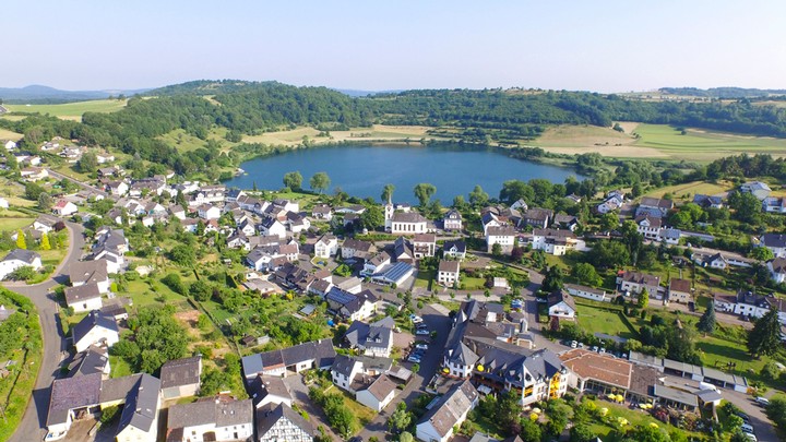 Michels Wohlfühlhotel - Luftaufnahme Maar mit Dorf 2